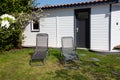 Small white wall grey door painted garden house with relax gray chair on green grass garden Royalty Free Stock Photo