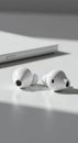 Small, white wireless earbuds placed on a smooth white surface. The design features Royalty Free Stock Photo