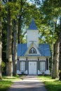 Small white wooden church in between trees in Latvia