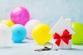 Small white wooden house decorated red bow ribbon with bunch of keys and balloons. Housewarming, gift, moving, buying a new home Royalty Free Stock Photo