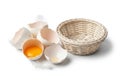 A small wicker basket is placed next to several broken eggshells, Royalty Free Stock Photo