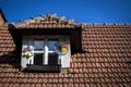 A small window decorated with windbreaks in the red roof