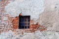 small window with a grid in an old brick wall and cracked dirty plaster. Royalty Free Stock Photo