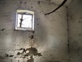 A small window at the top of the wall. Scary walls with cobwebs. Old church dormer. Halloween or haunted place. Prison cell with Royalty Free Stock Photo