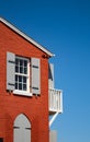 Small window with wooden shutters on the corner of an old red house Royalty Free Stock Photo