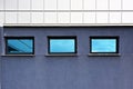 Small windows with reflection of sky on facade of modern building Royalty Free Stock Photo