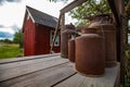 Small wood brown house of bus stop. Rusted milk tanks. Summer day. Green grass field and blue sky with clouds. Countryside Royalty Free Stock Photo