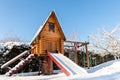 Small wood log playhouse teehouse hut snowcapped stairs ladder wooden slide children playground at park or house yard Royalty Free Stock Photo