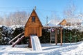 Small wood log playhouse teehouse hut snowcapped stairs ladder wooden slide children playground at park or house yard Royalty Free Stock Photo