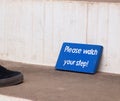 Small wood plate painted blue with hand written words `please watch your step`on a stair as waring sign for english language tour