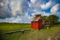 Small wood red house of bus stop. Wood bench. Summer day. Green grass field and blue sky with clouds. Royalty Free Stock Photo