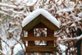 A small wooden bird house full of snow is hanging at a tree in the garden Royalty Free Stock Photo