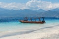 Small wooden boat on blue beach with cloudy sky and Lombok island on background. Gili Trawangan, Indonesia Royalty Free Stock Photo