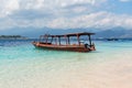 Small wooden boat on blue beach with cloudy sky and Lombok island on background. Gili Trawangan, Indonesia Royalty Free Stock Photo