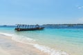 Small wooden boat on blue beach with cloudy sky and Lombok island on background. Gili Trawangan, Indonesia Royalty Free Stock Photo