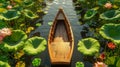 A small wooden boat in a pond with large lotus leaves and blooming flowers on both sides Royalty Free Stock Photo