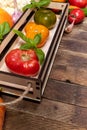 Small wooden box with color fresh ripe farm tomatoes on old rustic table with copy space. Royalty Free Stock Photo