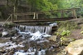 A small wooden bridge across a stream among thickets between the hills of the Carpathian Mountains Royalty Free Stock Photo