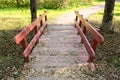 Small wooden brodge with red railings in a park in sunny day