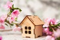 Small wooden cabin close-up and copy space. Miniature house, flowering branch in the spring. The concept of rush, purchase, exchan