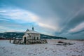 A small wooden Christian church stands among the snows and mountains.