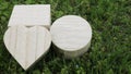 Small wooden closed casket in the shape of a heart, circle and cube on a green grass
