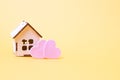 Small wooden decorative and two pink hearts on a yellow background Royalty Free Stock Photo