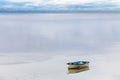 A small wooden dinghy moored on a calm bay of water as a storm passes by on the horizon Royalty Free Stock Photo