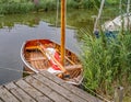 Small wooden dinghy moored up on a quiet river in rural Norfolk, UK