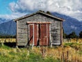 A small wooden farm shed with red corrugated iron doors