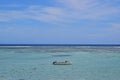 A small wooden fishing boat with two fishermen on a seaview with horizon that separates water and sky Royalty Free Stock Photo