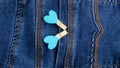 Small wooden heart clothespins fastened to a denim pocket. Small clothespins with blue hearts on the pocket of blue jeans Royalty Free Stock Photo