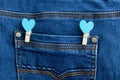 Small wooden heart clothespins fastened to a denim pocket. Small clothespins with blue hearts on the pocket of blue jeans Royalty Free Stock Photo