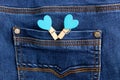 Small wooden heart clothespins fastened to a denim pocket. Small clothespins with blue hearts on the pocket of blue jeans Royalty Free Stock Photo
