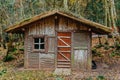 SMALL WOODEN HOUSE IN THE AUTUMN FOREST ON A CLOUDY DAY. SMALL WOODEN FARM BUILDING IN SCANDINAVIAN STYLE Royalty Free Stock Photo