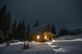 Small wooden house in the Carpathians, on the background of the winter forest at night Royalty Free Stock Photo
