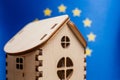 Small wooden house, European Union flag on background. Real estate concept, soft focus Royalty Free Stock Photo