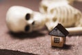 Small wooden house and human skeleton close-up. The concept of an unfulfilled dream in buying a home Royalty Free Stock Photo