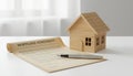 Small wooden house model next to a mortgage agreement and pen Royalty Free Stock Photo