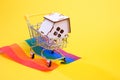 Small wooden house in a shopping trolley stands on the flag of the lgbt community, Royalty Free Stock Photo