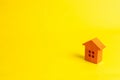 A small wooden house stands on a yellow background. The concept Royalty Free Stock Photo