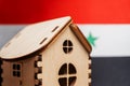 Small wooden house, Syria flag on background. Real estate concept, soft focus Royalty Free Stock Photo