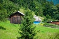 Small wooden houses at the foot of the mountain. Around the green trees and grass. Royalty Free Stock Photo