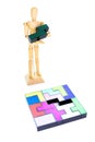 Small wooden mannequin holding the one piece needed to solve the puzzle, isolated on white background