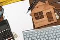 Small Wooden Model House on a Desk with Blank Note Book Royalty Free Stock Photo