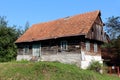 Small wooden old family house with dilapidated boards and broken roof with missing roof tiles on top of small hill Royalty Free Stock Photo