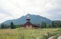 Small wooden orthodox temple in the mountains. Made from thick logs. Brown roof, cross on the dome Royalty Free Stock Photo