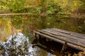 A small wooden pier on a quiet lake on an autumn day. Autumnal colorful landscape Royalty Free Stock Photo