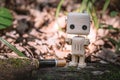 A small wooden robot next to an alkaline battery