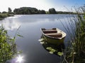 Small wooden rowing boat on pond in sunshine Royalty Free Stock Photo